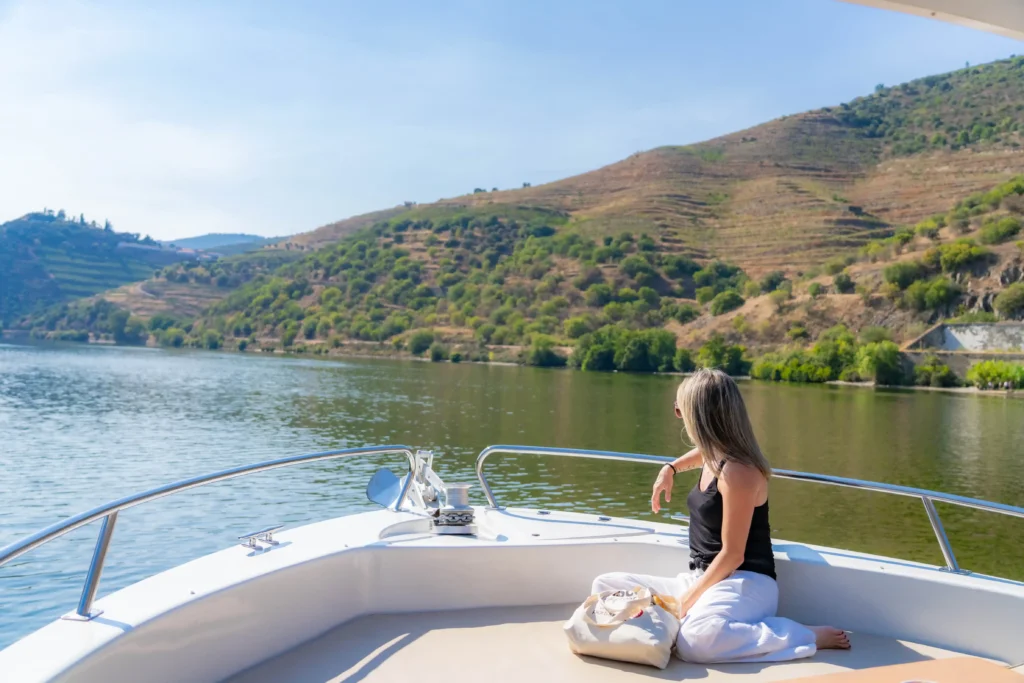Barco turístico a navegar no rio Douro rodeado por vinhas em socalcos no Vale do Douro