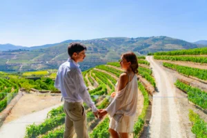 Casal a visitar quintas do Douro para enoturismo com vista para vinhas em socalcos e paisagem do Vale do Douro